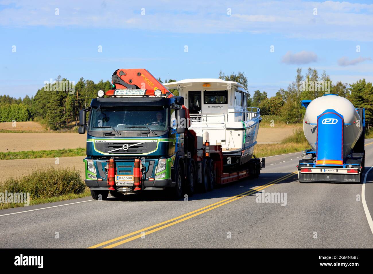 Green Volvo FM semi trailer transports recreational boat as oversize load, tank truck drives in opposite direction. Salo, Finland. September 9, 2021 Stock Photo