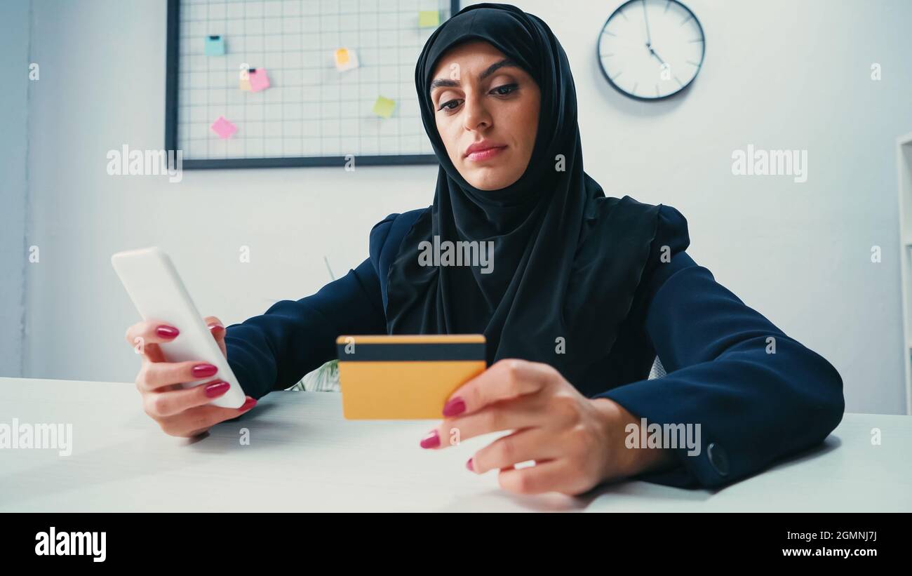 Muslim businesswoman using smartphone and credit card Stock Photo
