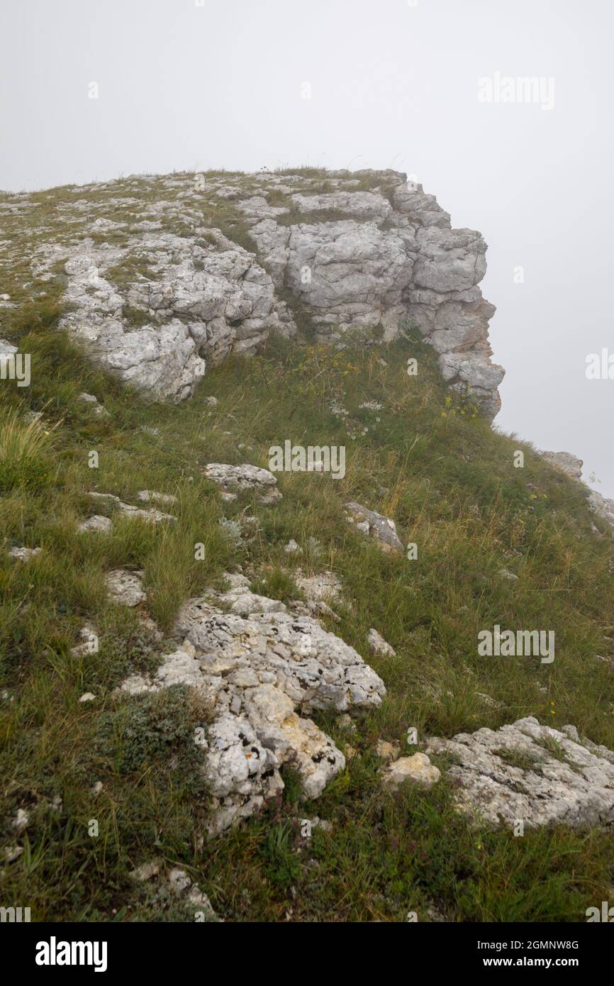 Stony slopes of the Ai-Petri mountain in dense fog. The slope is overgrown with grass. Stock Photo