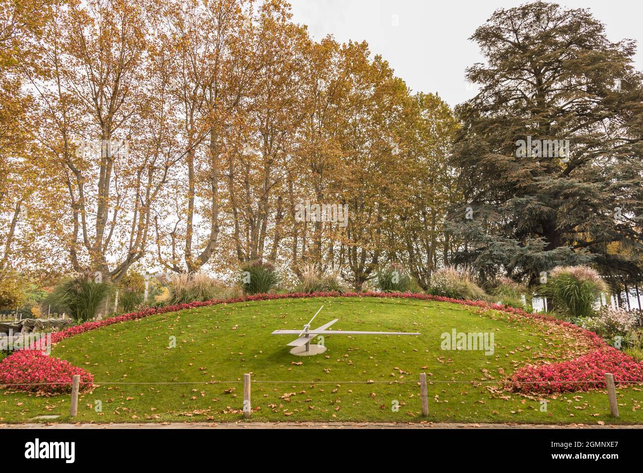 A flower clock on lawn on a park with many trees around at day. Lausanne, Switzerland Stock Photo