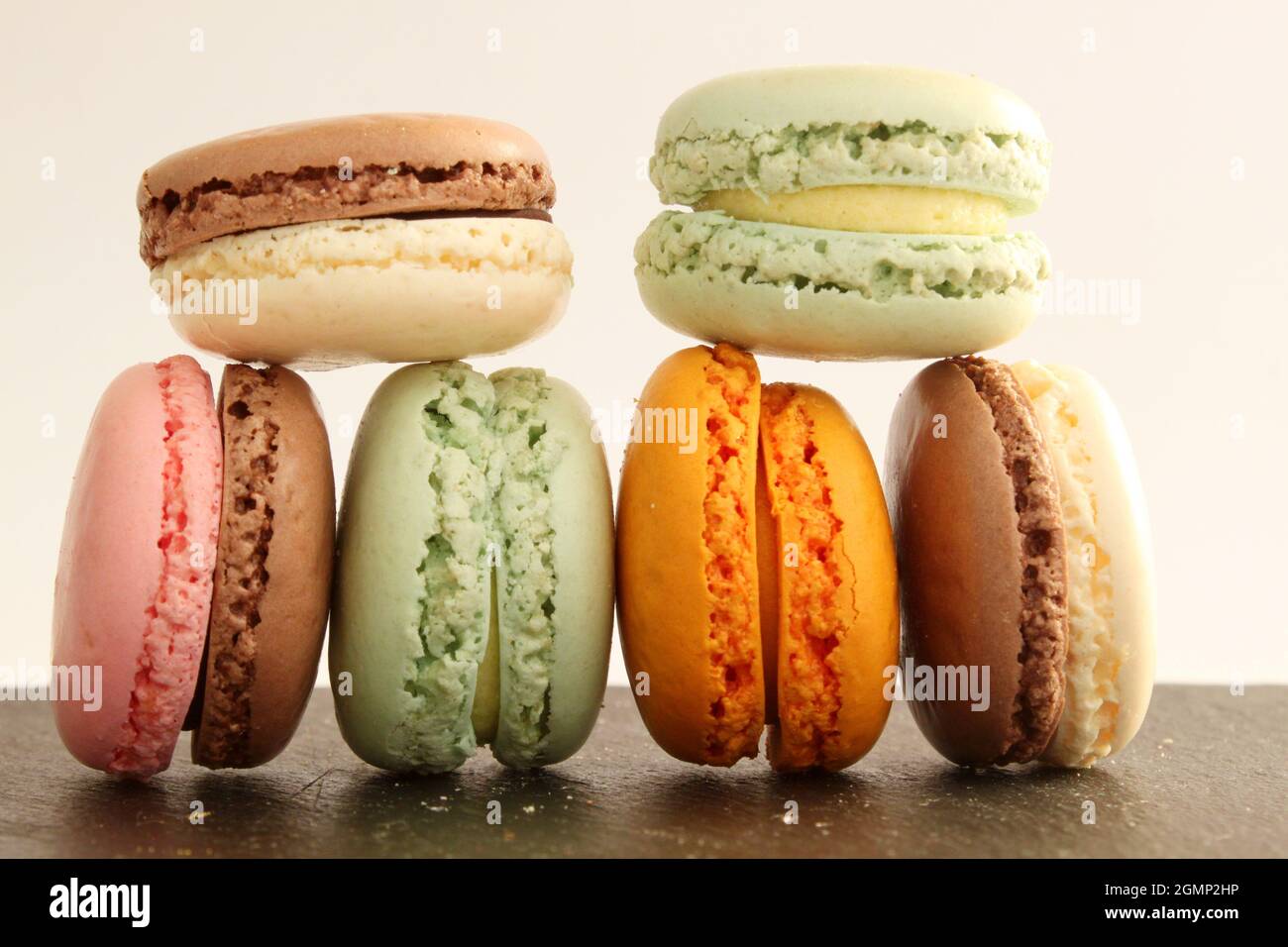 Different multicolor macarons on black stone plate Stock Photo
