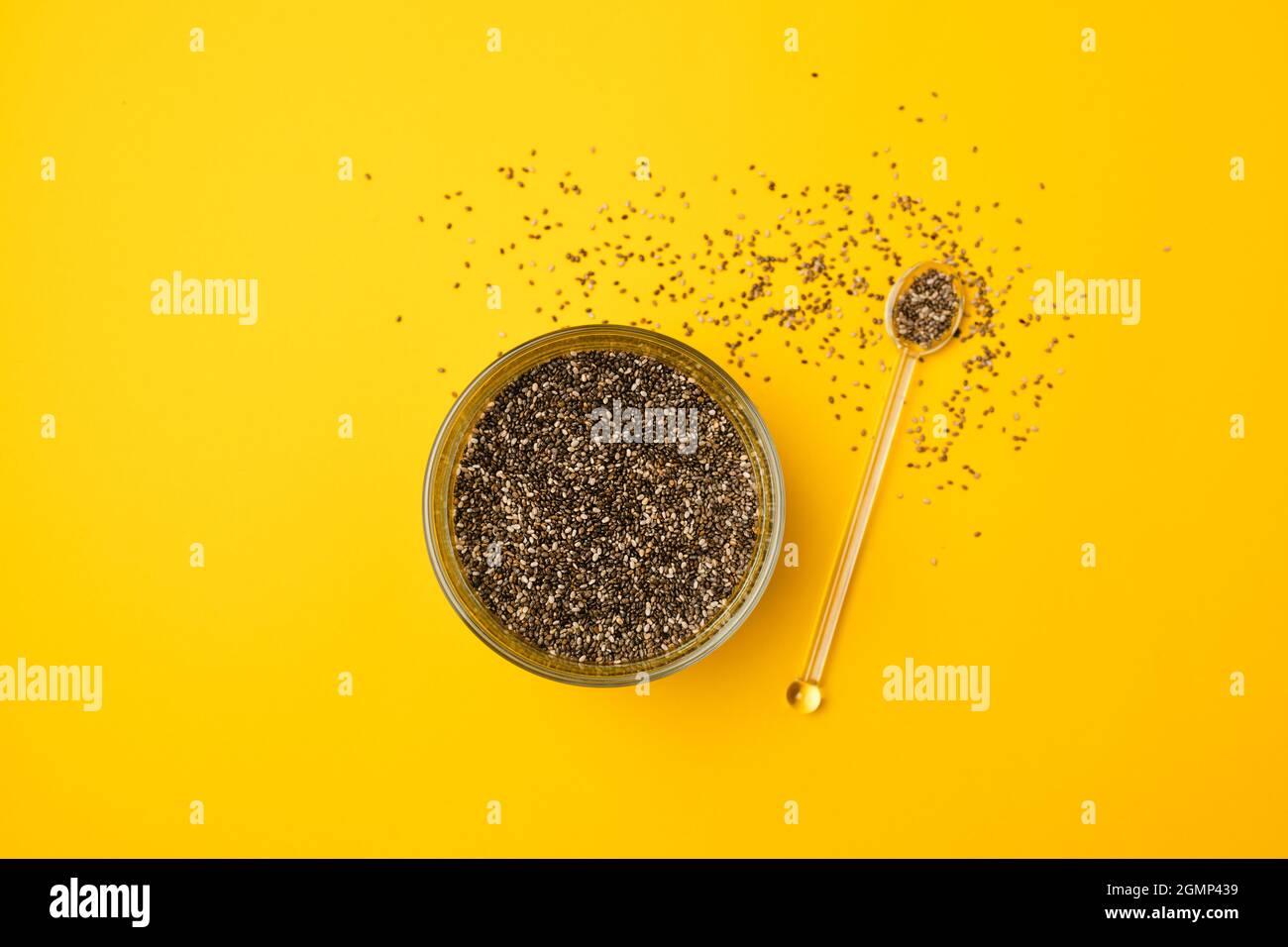 Glass bowl and spoon with chia seed son a bright yellow background with copy space, closeup, view from above Stock Photo