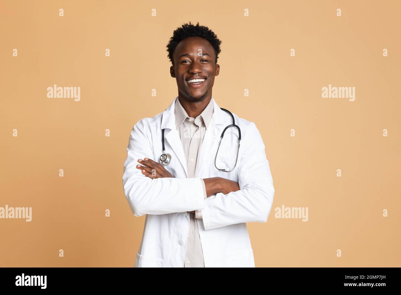 Portrait Of Confident Black Male Doctor In Uniform Posing Over Beige Background Stock Photo