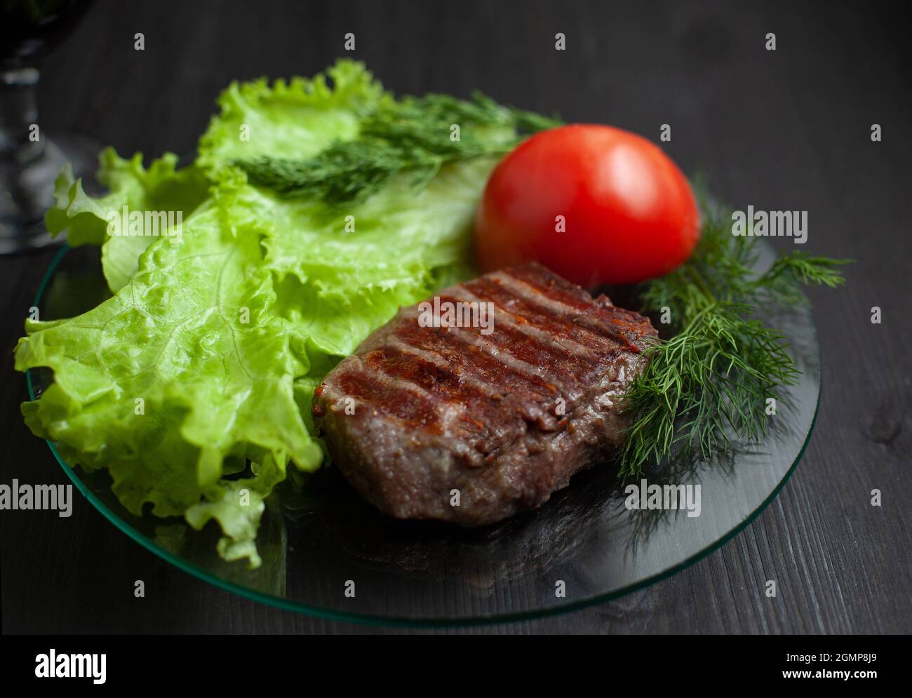 Grilled steak with vegetable salad and herbs. Concept for a tasty and healthy meal. Dark bakground Stock Photo