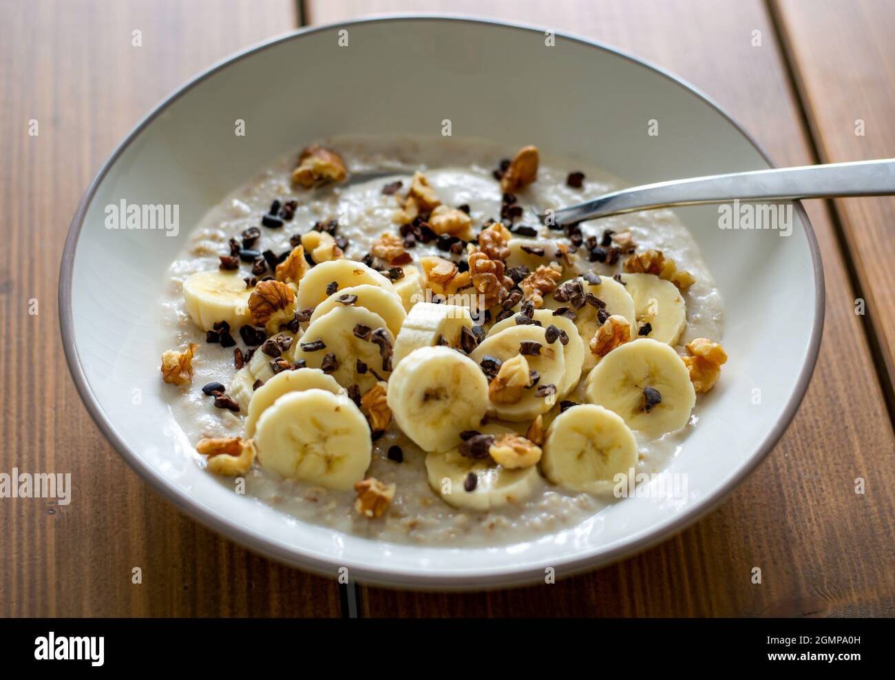 Healthy oatmeal porridge with banana, walnuts and cacao nibs. Stock Photo