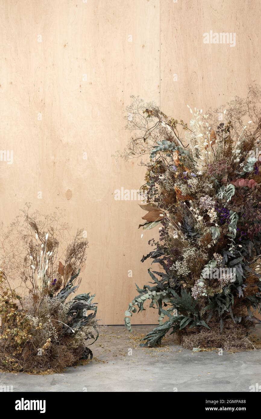 Large floral arrangement bouquet of dried flowers on the background of a wood wall and cement floor. The concept of inspiration, congratulations, autu Stock Photo