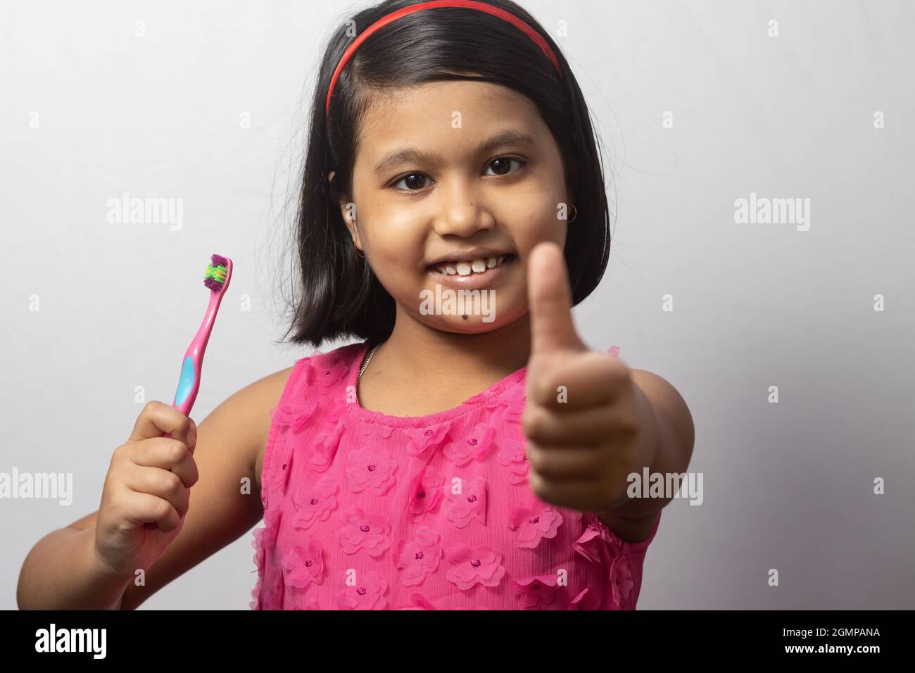Portrait of an Indian girl child showing thumbs up while brushing teeth ...