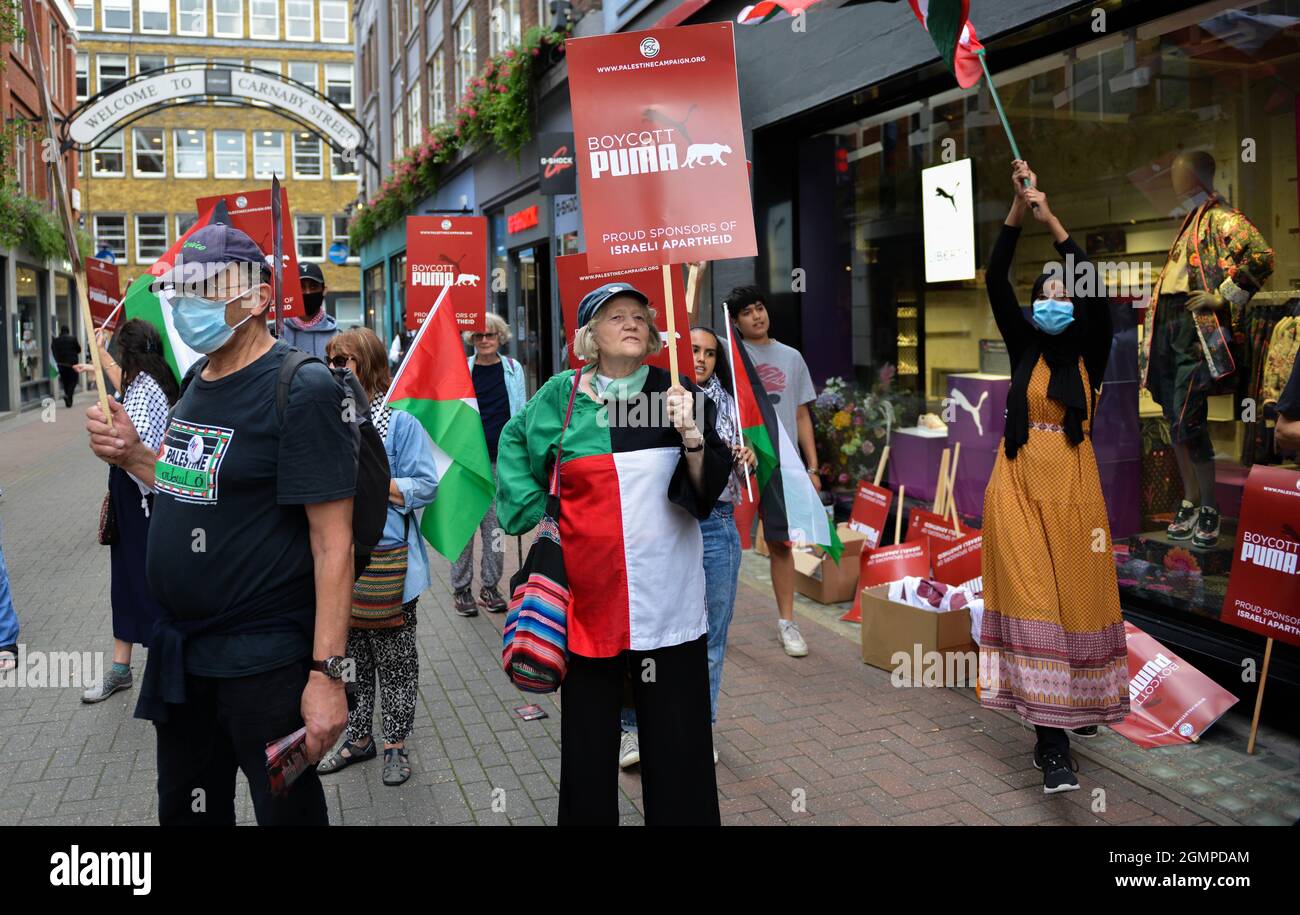 Protesters with banners are taking part in Boycott Puma protest at front of Puma flagship store on Carnaby Street, London. Stock Photo