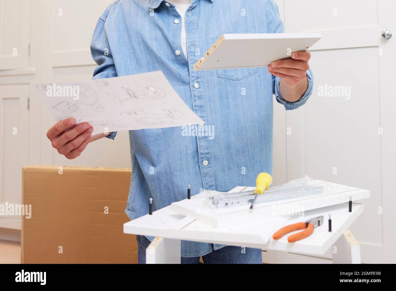Close Up Of Man Reading Instructions And Putting Together Self Assembly