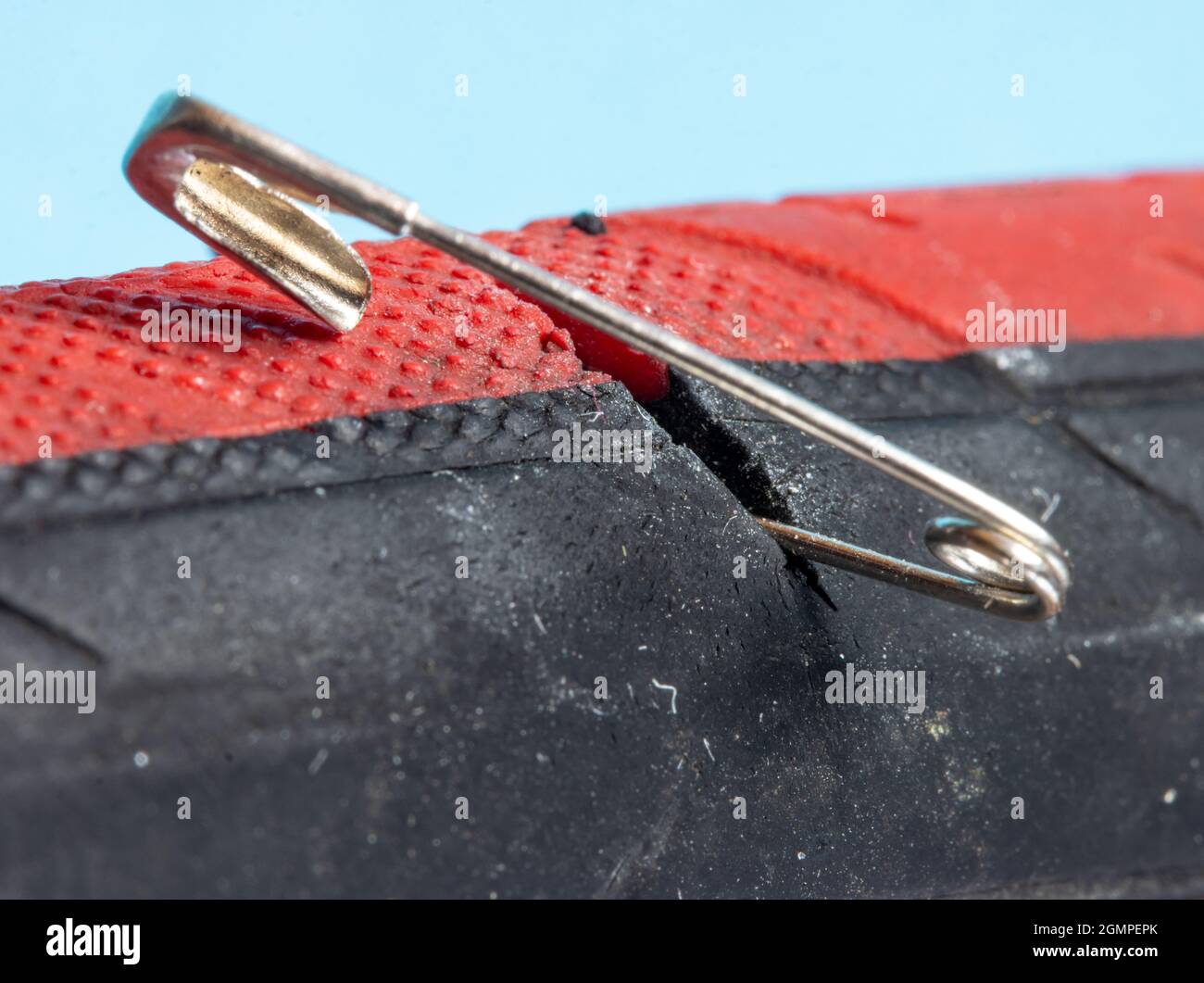 The bicycle tire is damaged by a safety pin, close up view. Stock Photo