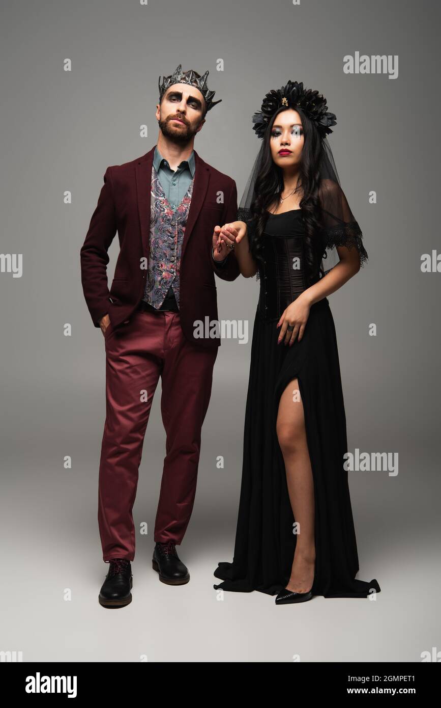 elegant interracial couple in vampires halloween costumes holding hands ...