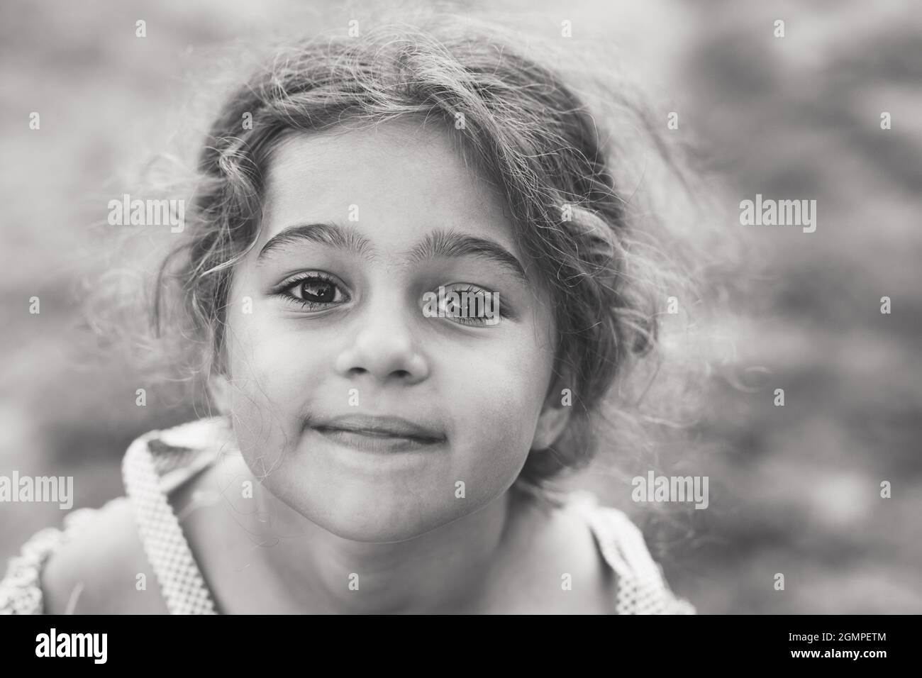 Black and white Portrait of smiling cute little girl at summer park. Happy child looking at the camera Stock Photo