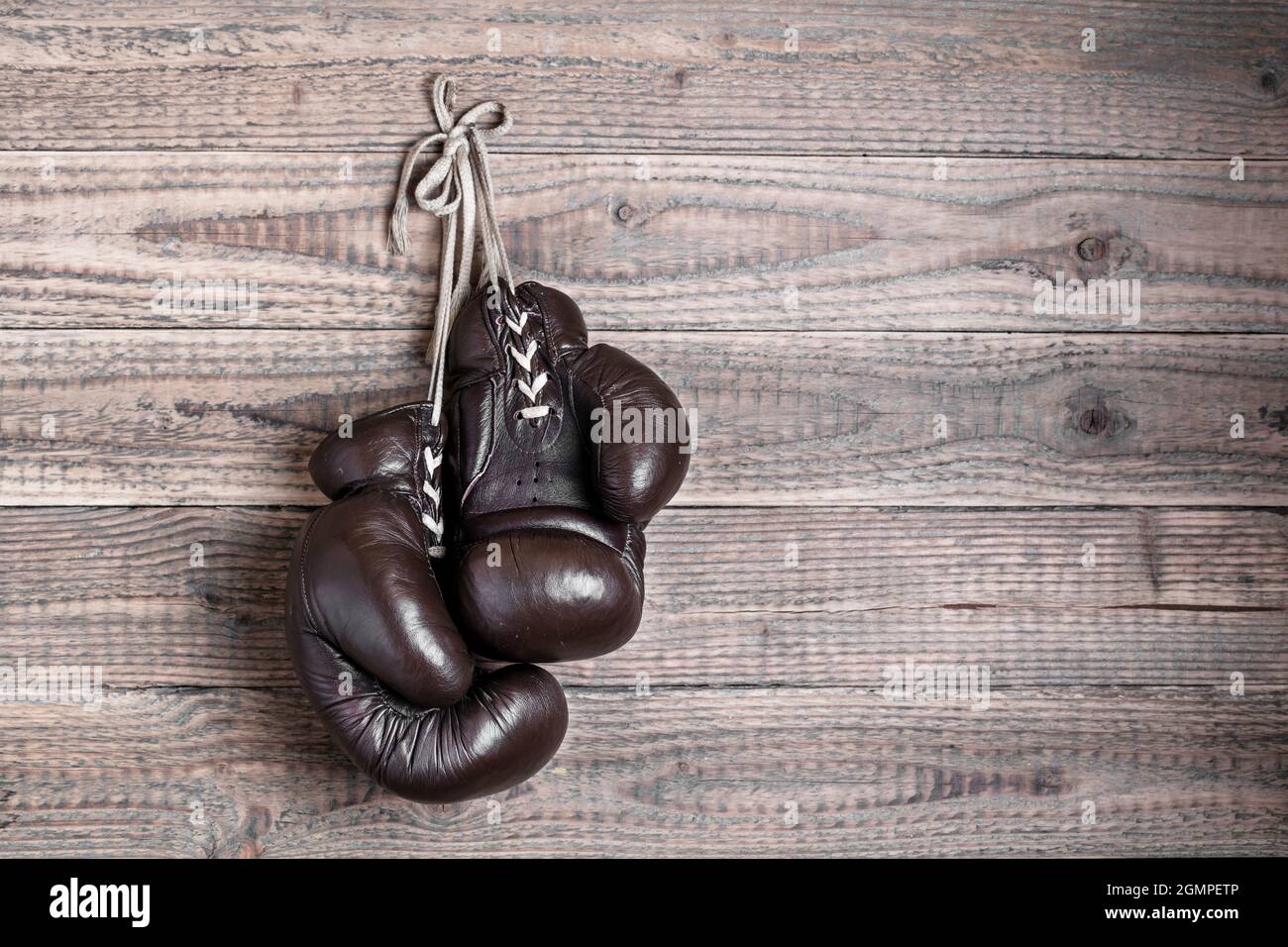 old boxing gloves hanging in front of rustic wooden wall Stock Photo