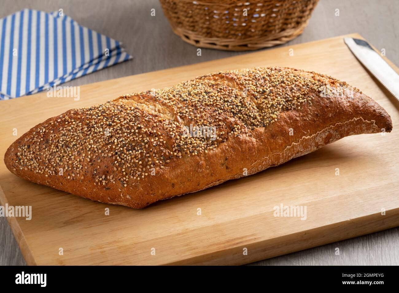 Whole traditional sourdough loaf of bread in a special shape with seeds on a cutting board Stock Photo