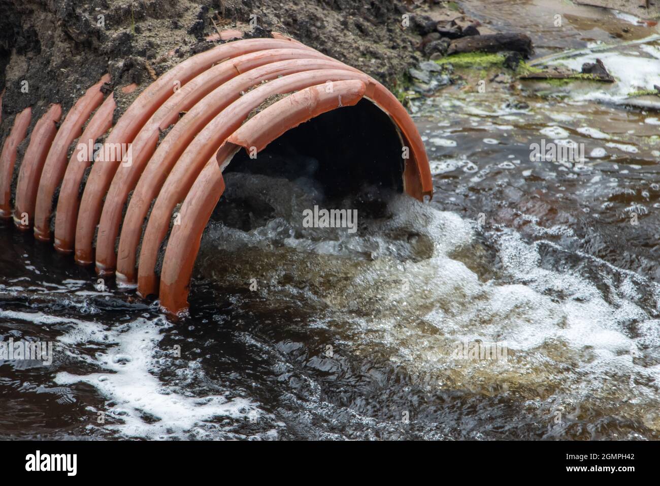 A stream of water flows from a large flexible pipe - hose. Stock Photo
