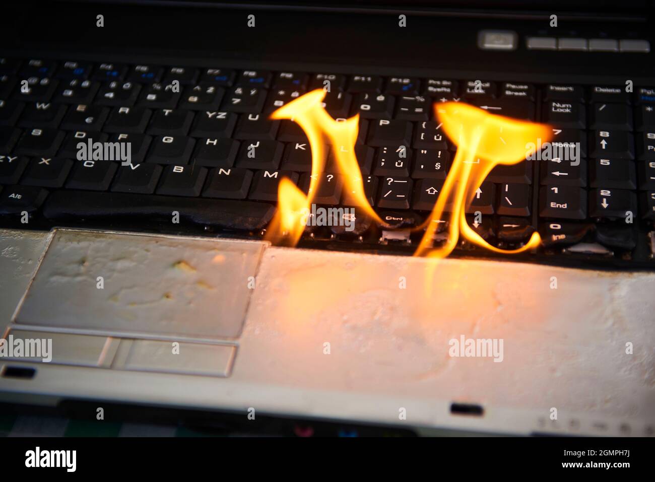 Laptop burning in flames on a desk, fire hazard. losing valuable data