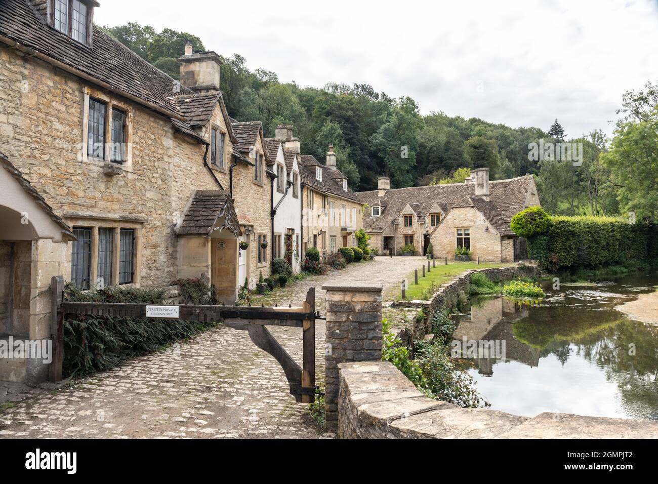 The picturesque traditional stone cottages alongside By Brook river bridge in the unspoilt Cotswold village of Castle Combe, Wiltshire, England, UK Stock Photo