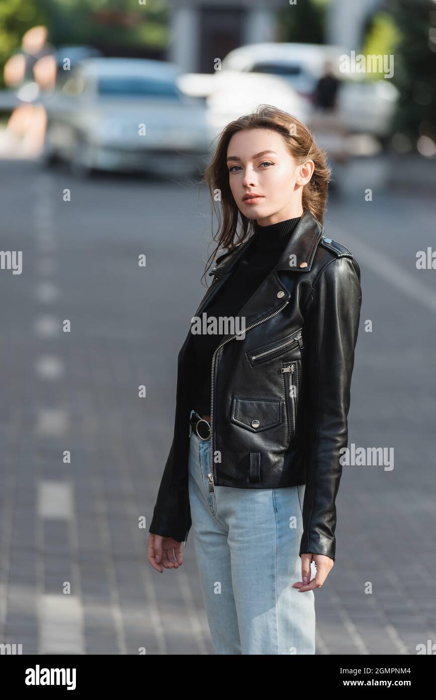 pretty young woman in black leather jacket standing outside Stock Photo ...