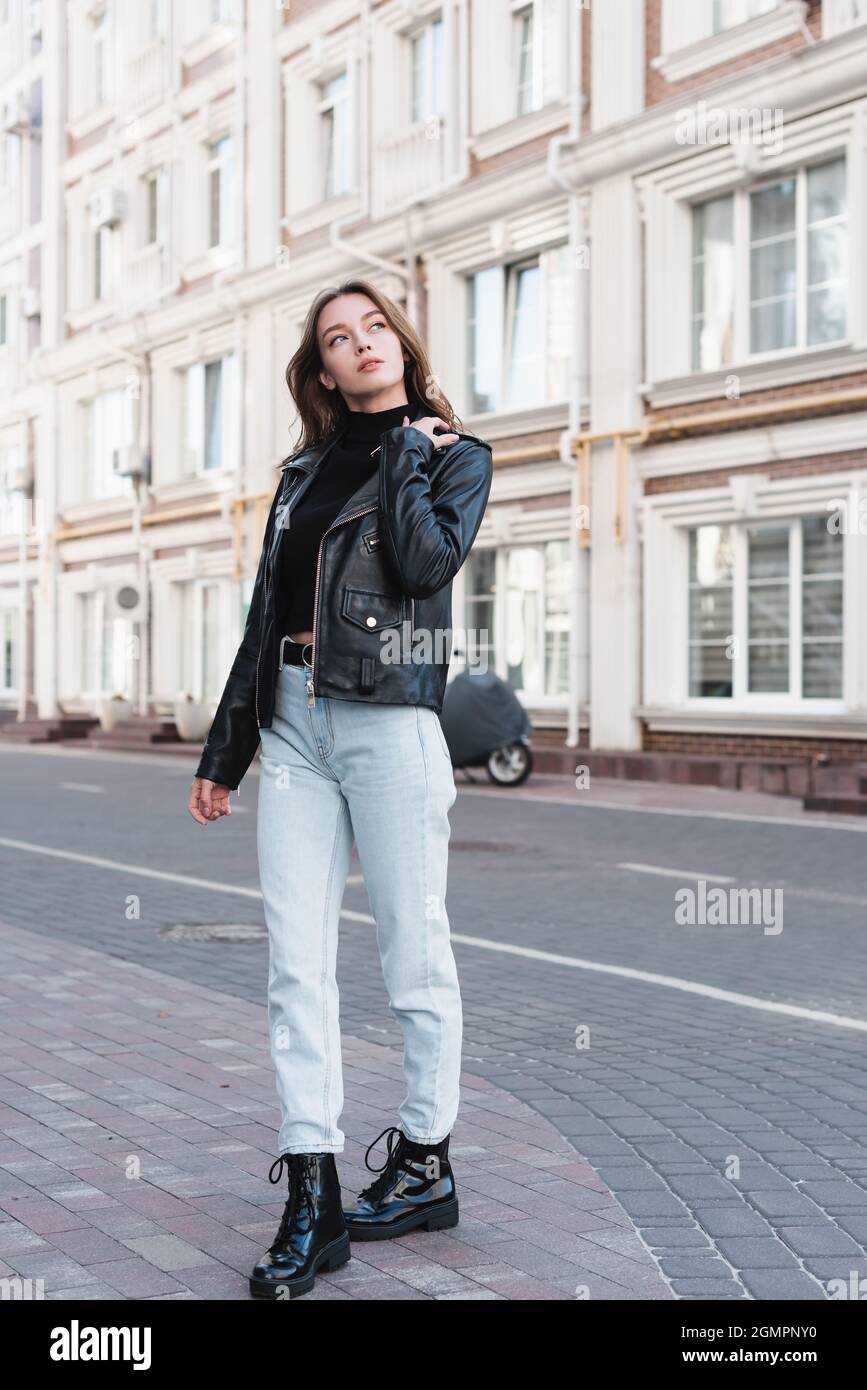 full length of stylish young woman in black turtleneck and leather jacket  on urban street of europe Stock Photo - Alamy