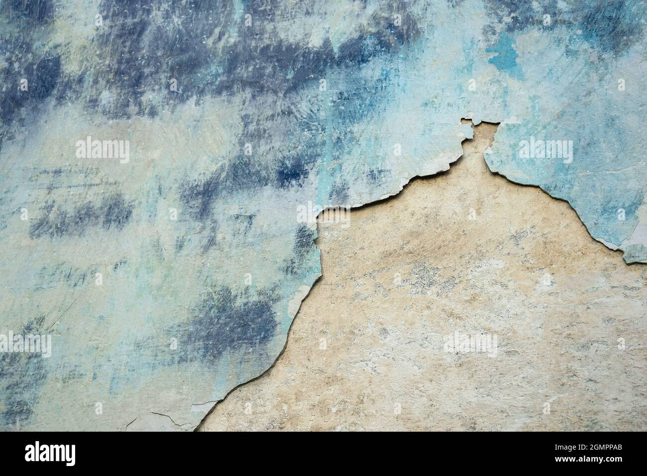 Wall of old building with partially fallen off plaster in gray and blue colors. Space is divided into two parts of different structures. Stock Photo