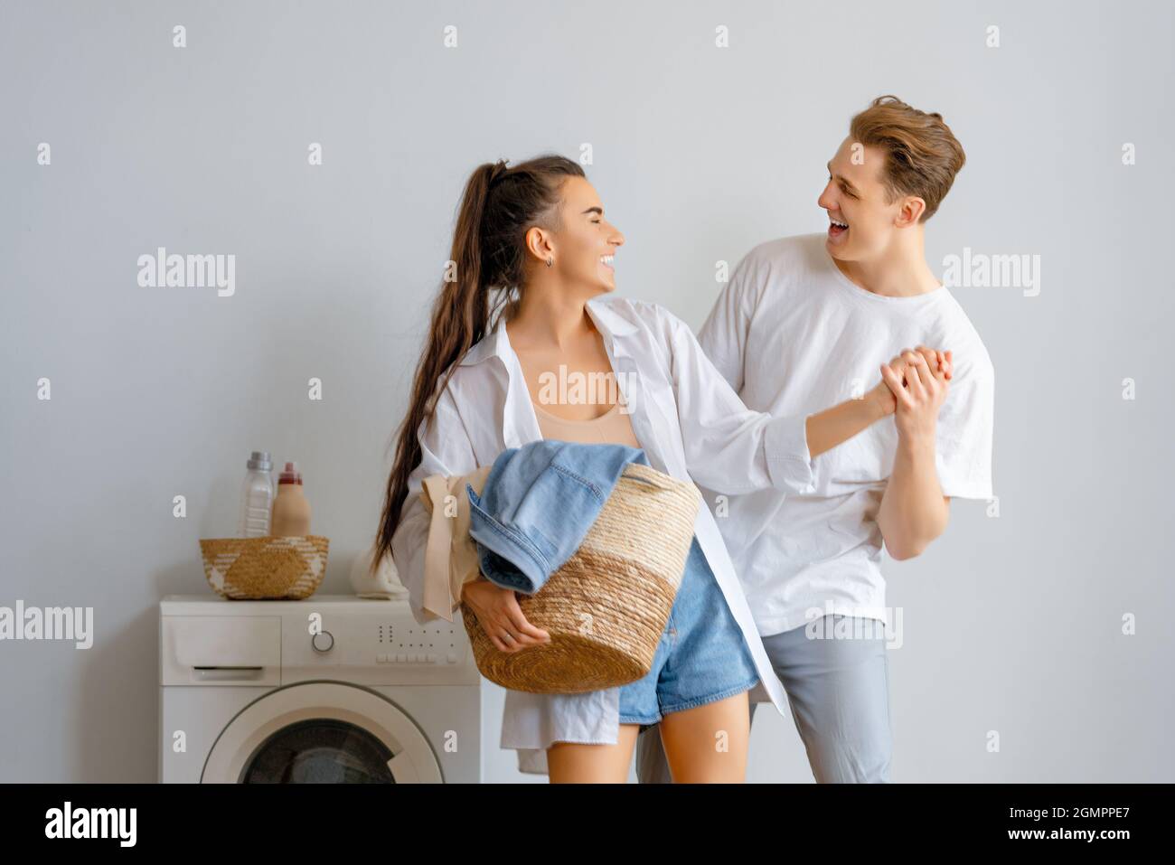 Beautiful young loving couple is smiling while doing laundry at home ...