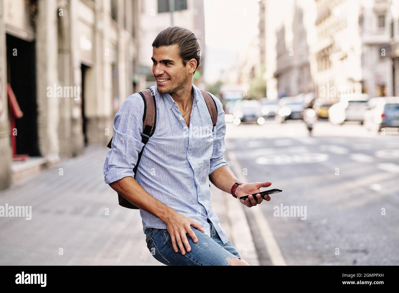 young handsome man smiling with smartphone at via laietana in Barcelona Stock Photo