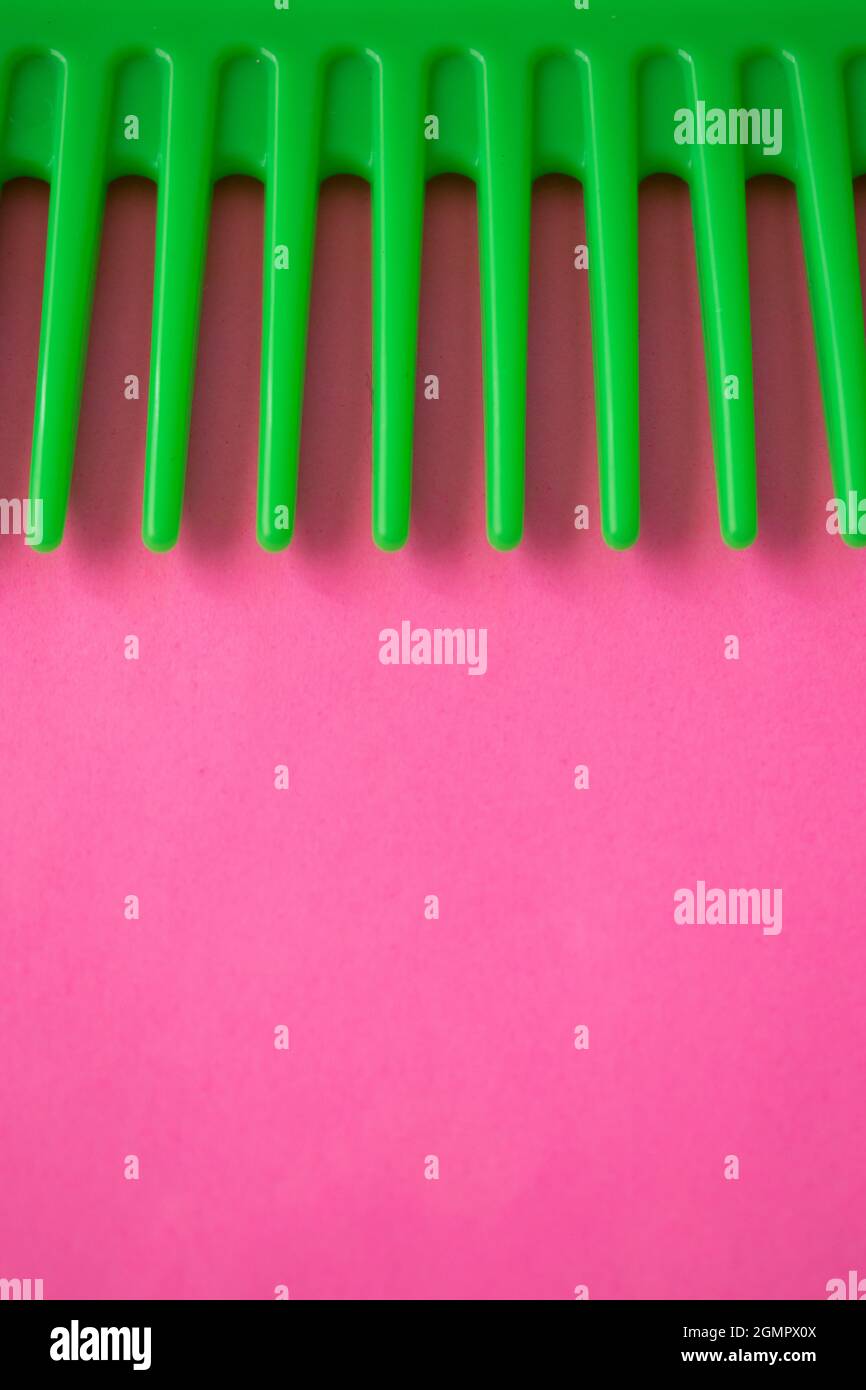 Close up of a green plastic comb on a pink surface Stock Photo