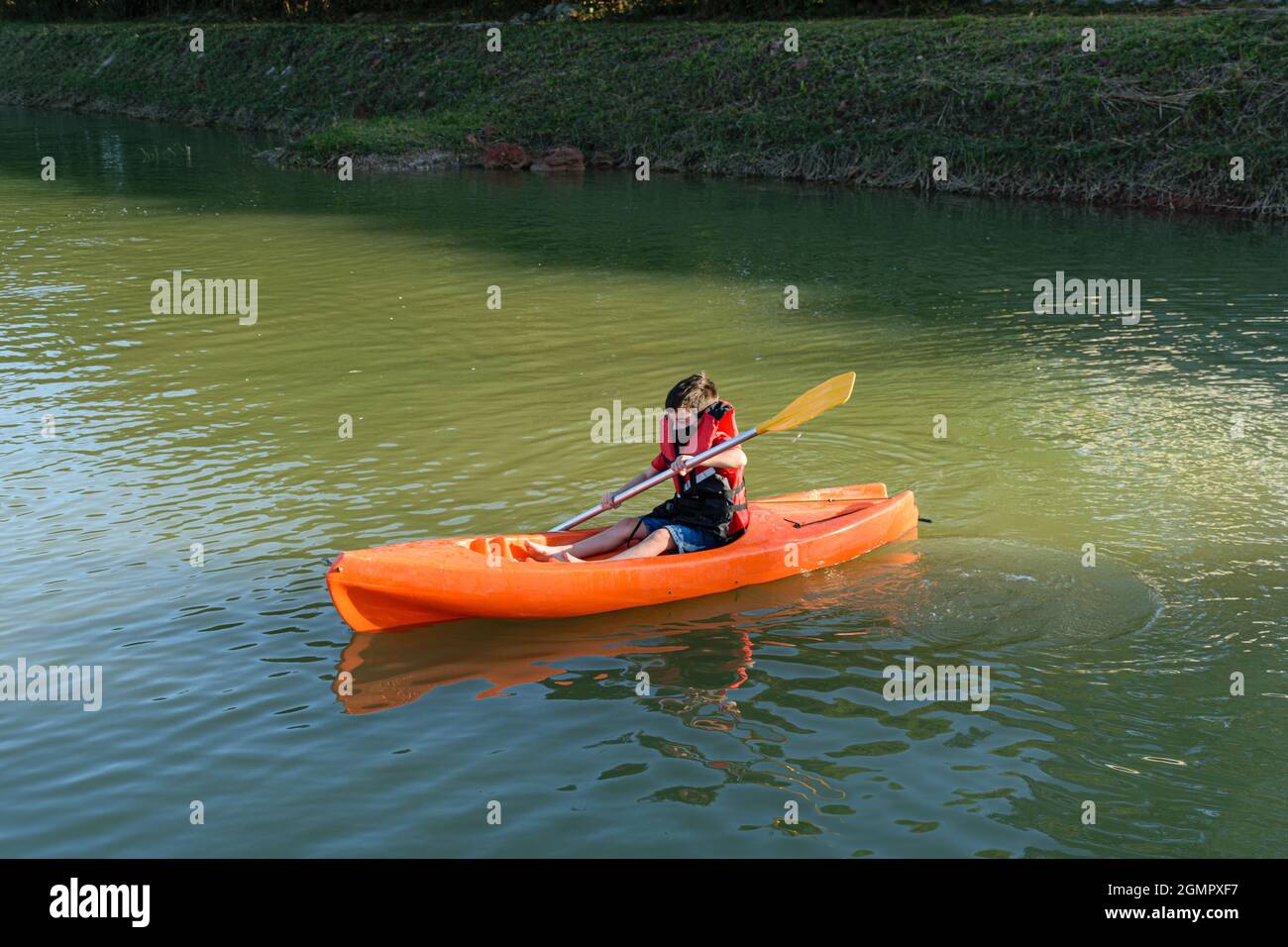 8 year old Brazilian child learning to use a kayak in a small river.d Stock Photo