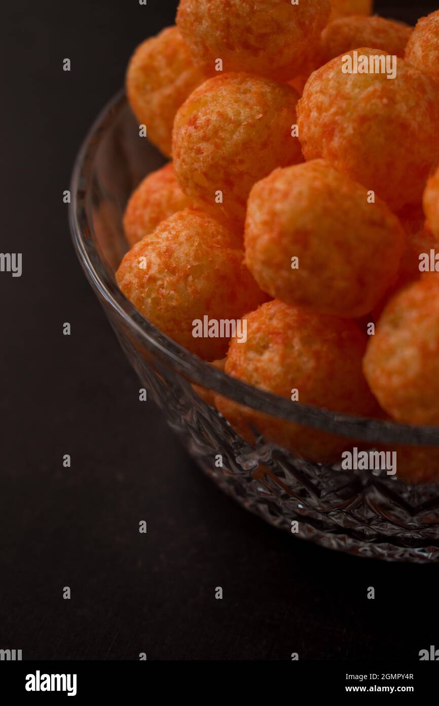 Cheese snack from a glass pot with cheese sticks and cheese balls on a black wooden table Stock Photo