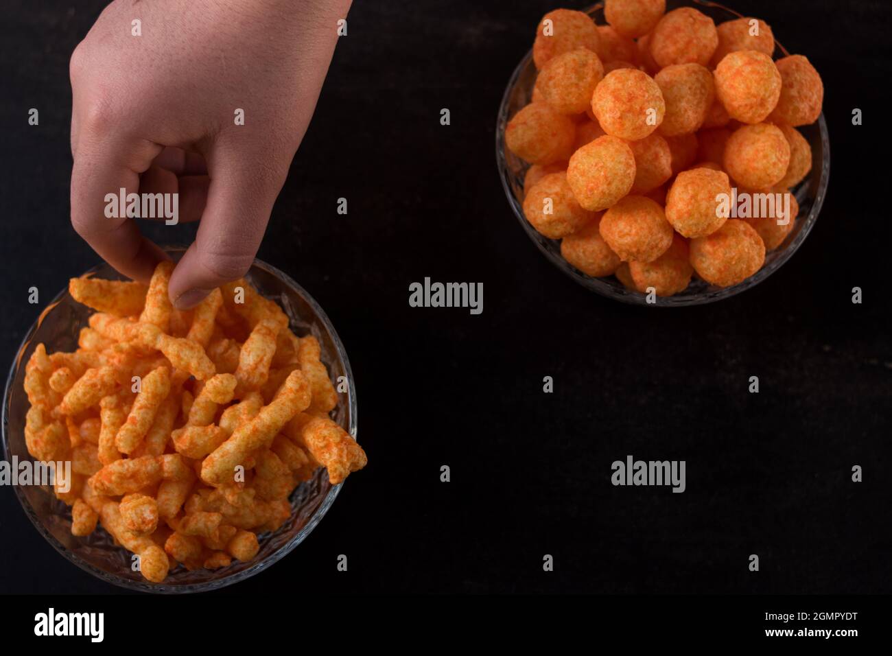 Cheese snack from a glass pot with cheese sticks and cheese balls on a black wooden table Stock Photo