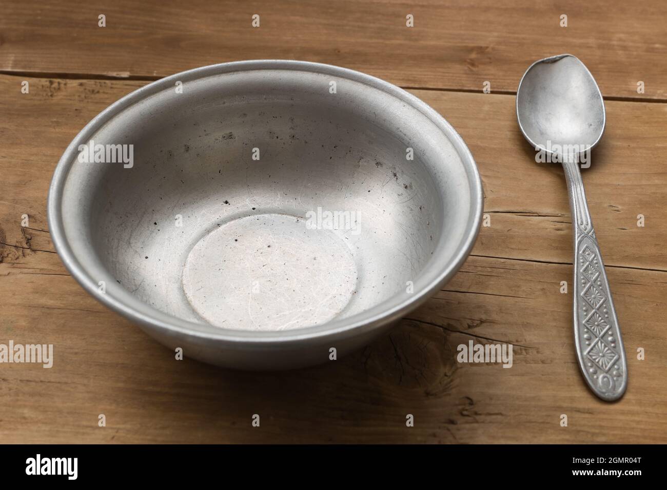 Empty aluminum bowl with spoon on the old wooden table Stock Photo