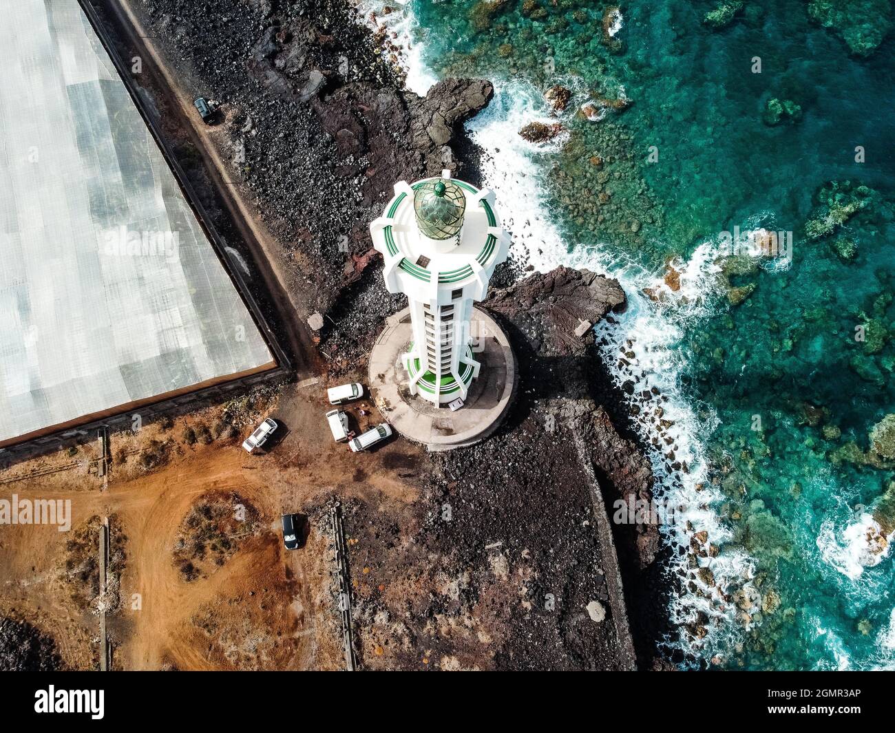 Aerial top view of lighthouse, rocks and ocean waves in a volcanic ...