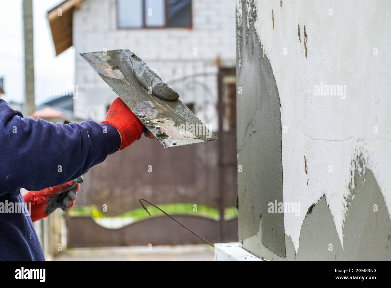 Construction worker covering house wall with adhesive cement glue