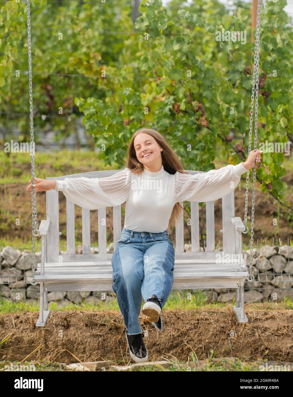 happy kid sitting on swing in park, summer Stock Photo