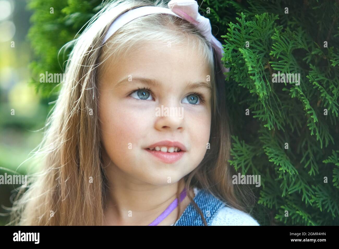 Portrait of pretty child girl standing outdoors in summer park smiling ...