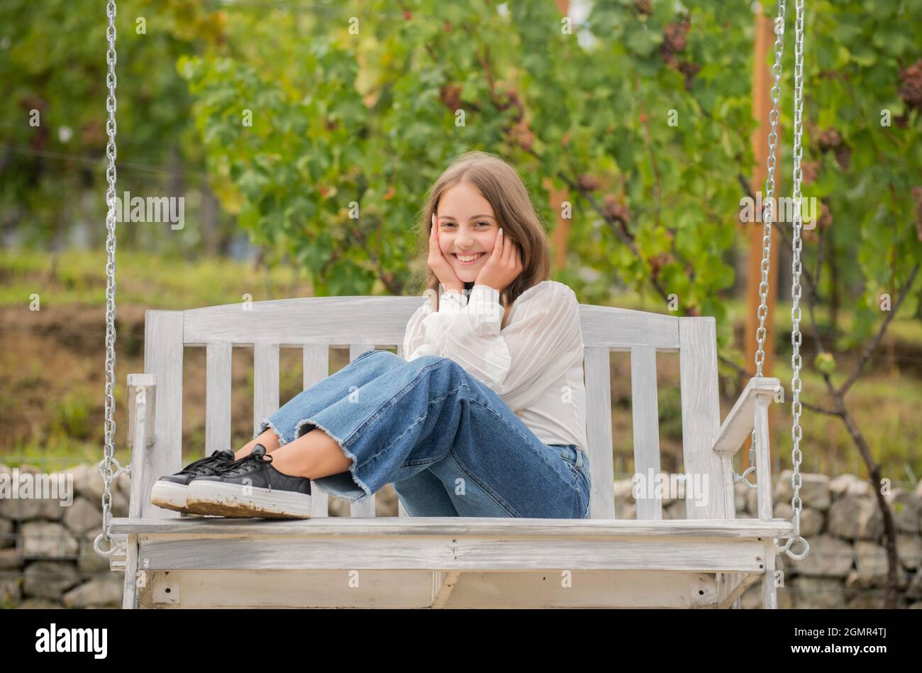 cheerful teen girl having free time outside on swing, relaxation Stock Photo