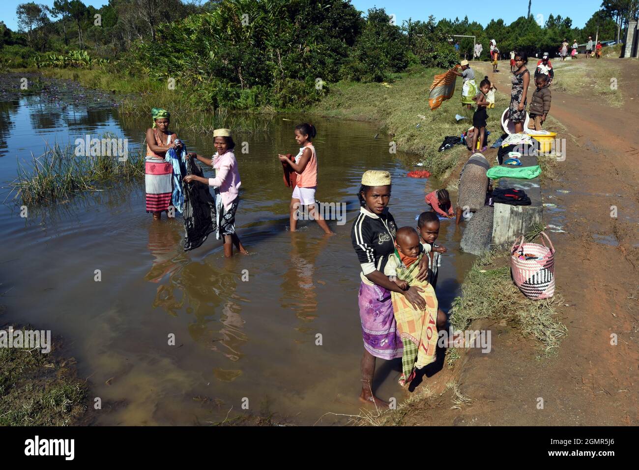 Women and Children bathing and washing clothes in a pond at the village of KELILALINA in the highlands of Madagascar Stock Photo