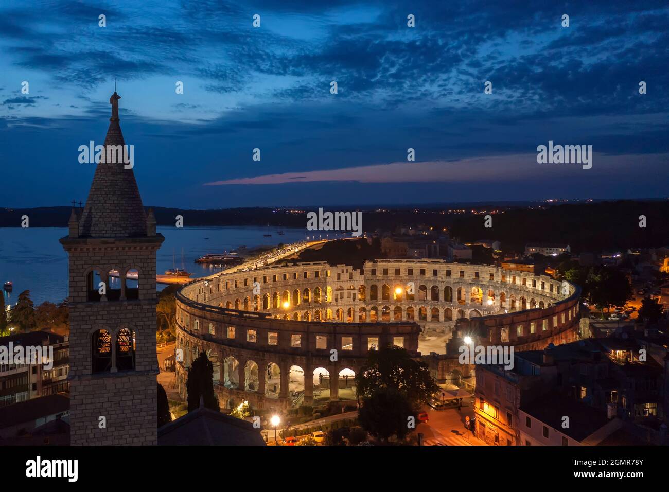 an aerial view of Pula aphitheatre by night, on left side bell tower of St. Antun church, Istria, Croatia Stock Photo