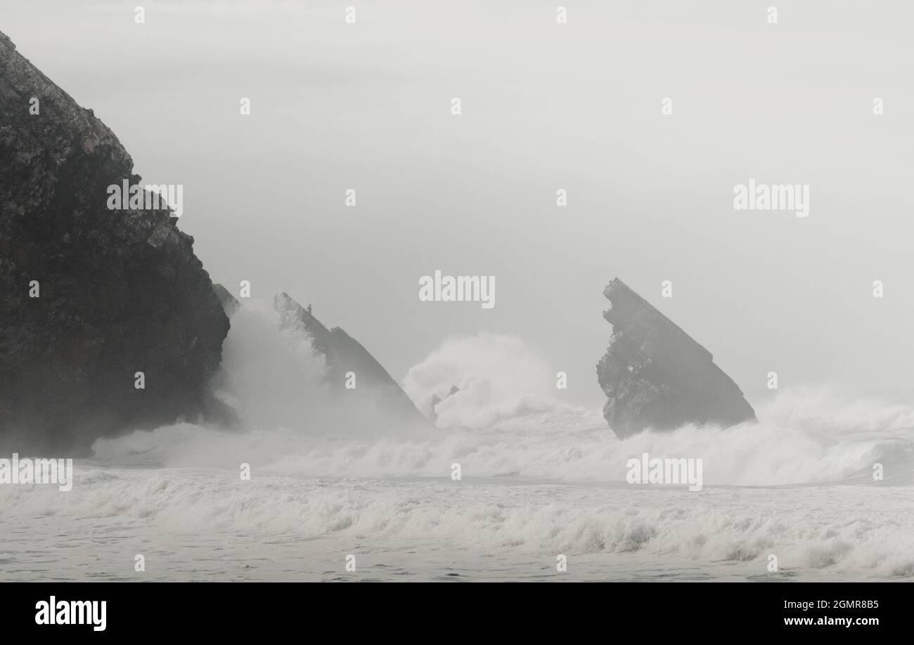 Grayscale shot of sea waves and a rocky shore on a foggy day Stock ...