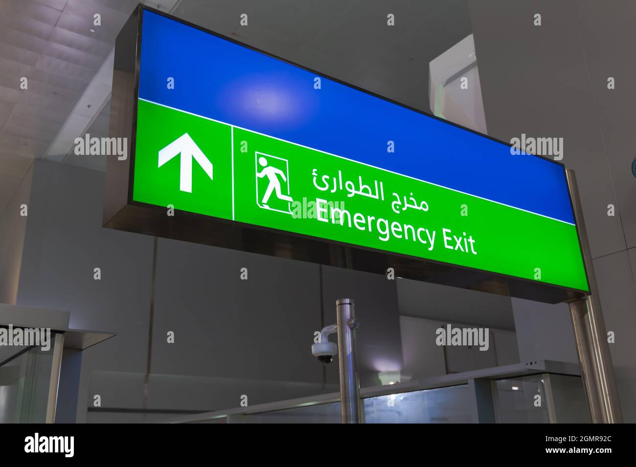Emergency exit sign in English and Arabic glowing green at airport