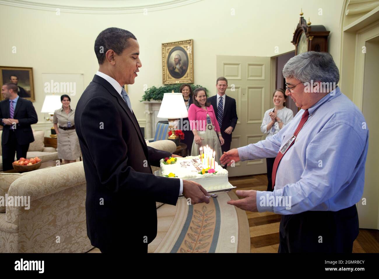 President Barack Obama presents a birthday cake April 15, 2009, to senior advisor Pete Rouse in the Oval Office. Official White House Photo by Pete Souza Stock Photo