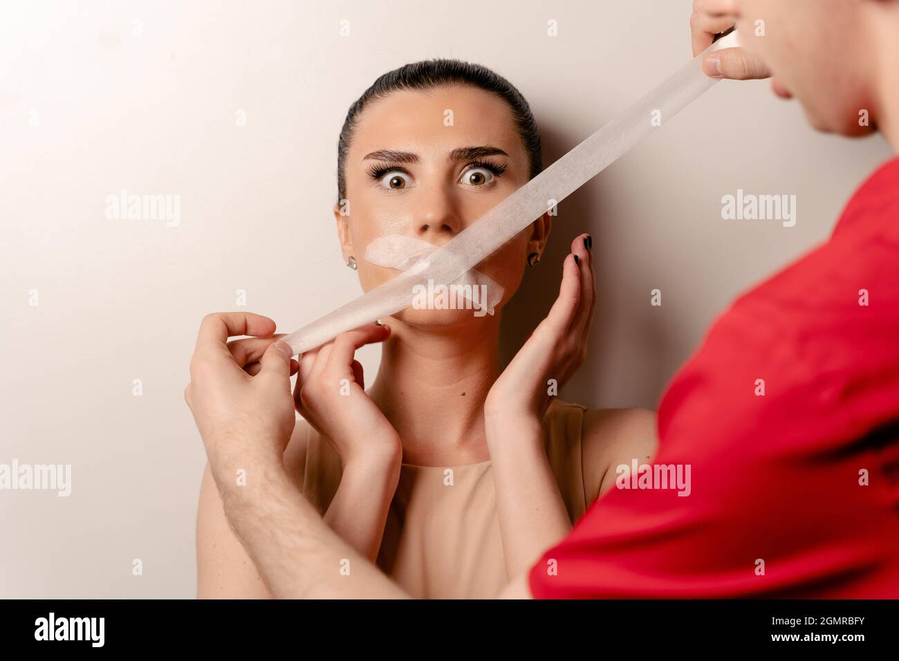 Model with glued mouth. Man covers woman mouth with tape. Stop talking Stock Photo