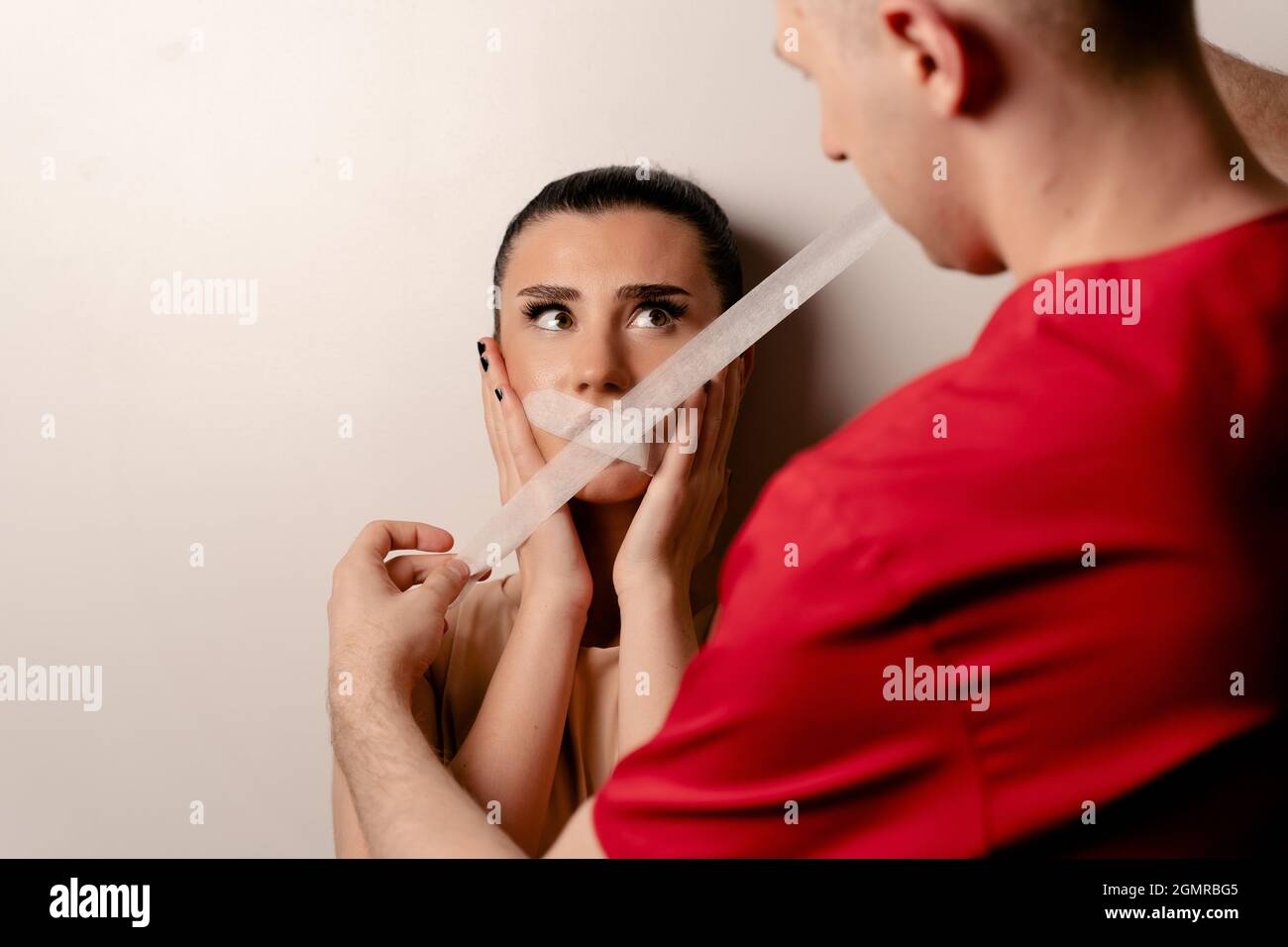 Model with glued mouth. Man covers woman mouth with tape. Stop talking Stock Photo