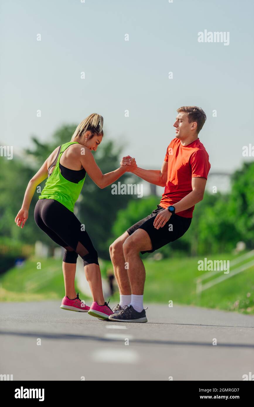 Attractive female helping her male running partner to get up from ...