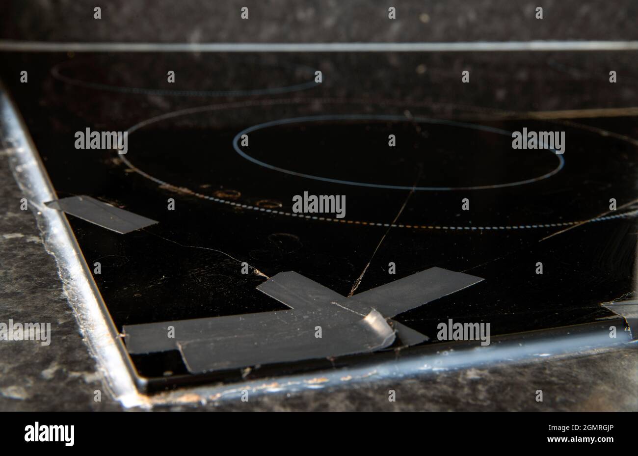 Home disasters: cracked broken ceramic hob covered with tape Stock Photo