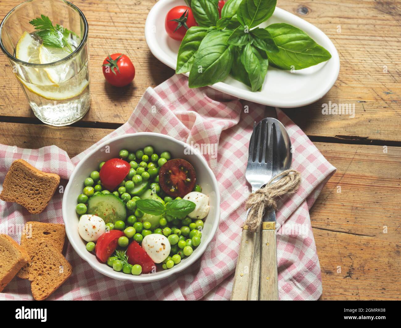 Salad vegetarian. Fresh vegetable salad with tomato, cucumber, basil, green peas, mozzarella cheese. Stock Photo