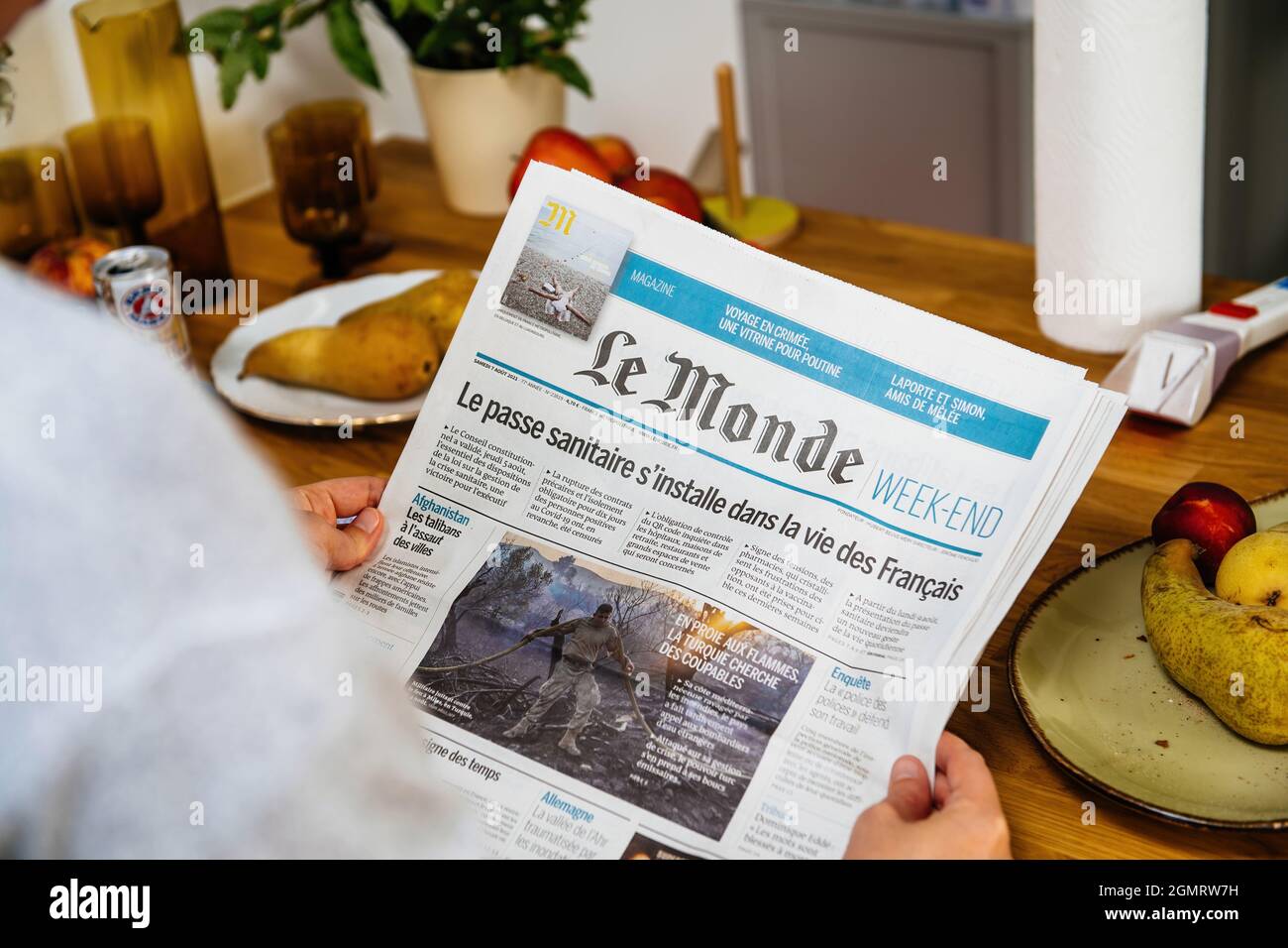 Woman reading in the kitchen early in the morning Le Monde newspaper Stock Photo