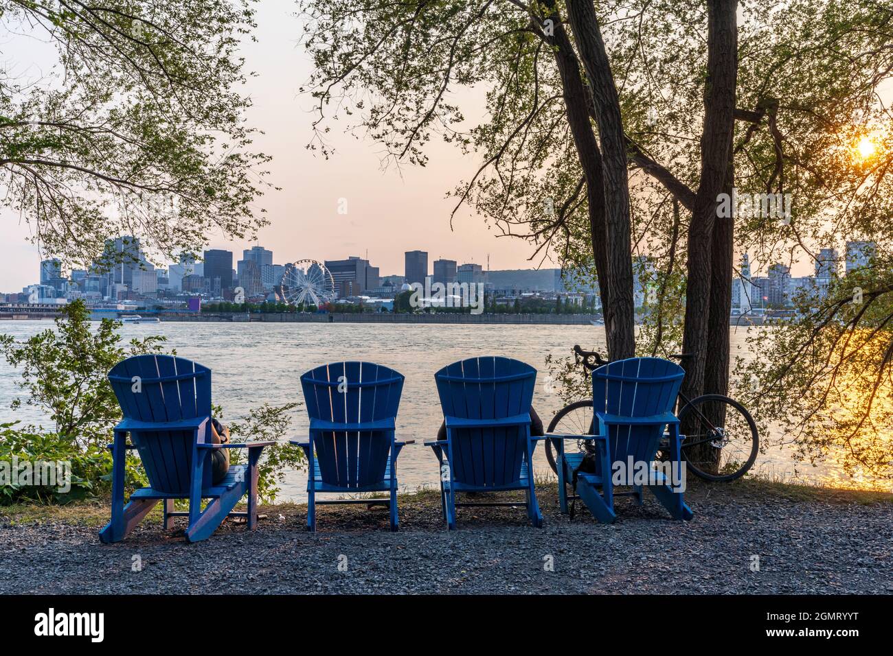 Blue chairs along the coast in the Jean-Drapeau park in sunset time. Saint Helens Island. Montreal, Quebec, Canada. Stock Photo