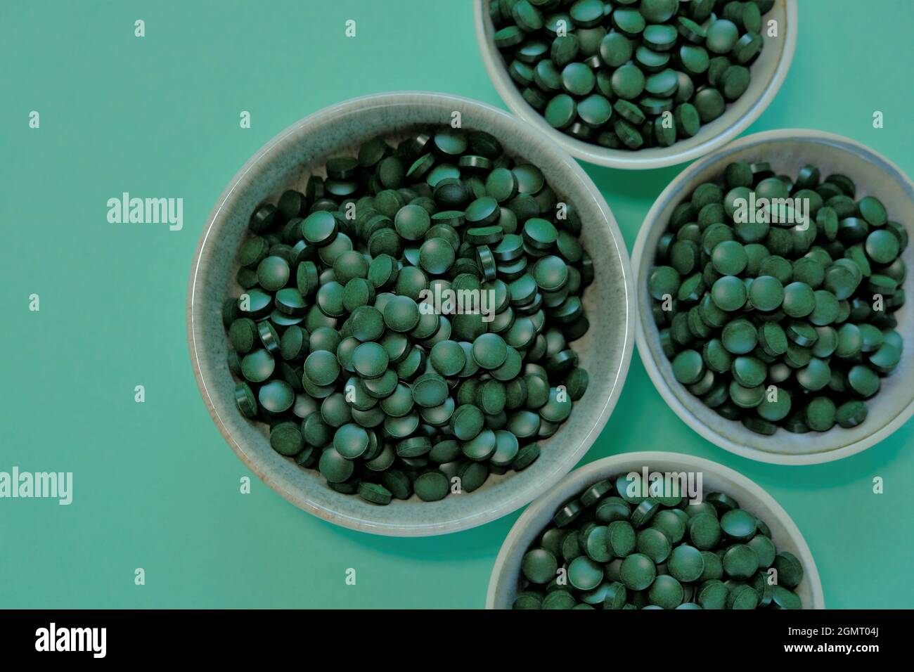 Spirulina algae tablets. Spirulina pills in cups on a green background.  Vegetarian omega three. source of amino acids and omega 3.Omega three Stock  Photo - Alamy