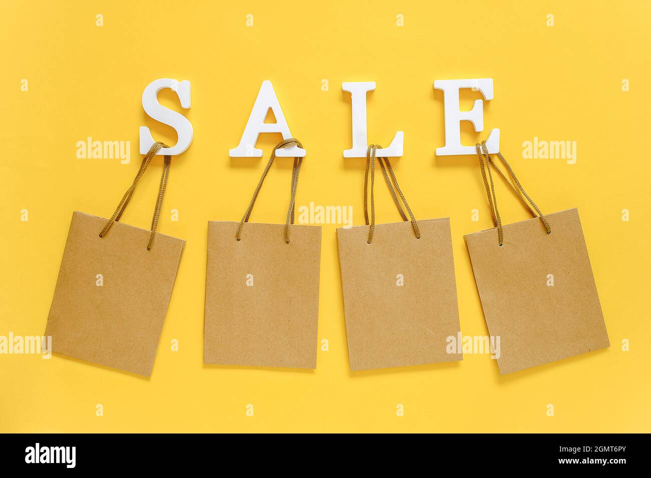 Text SALE from white volume letters and blank shopping bags on yellow background. Top view Flat lay Mockup Concept discount. Creative template for you Stock Photo